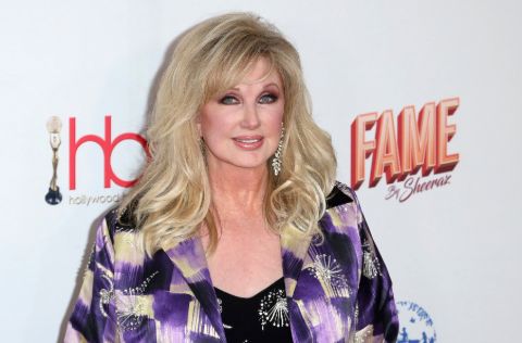 Morgan Fairchild in a purple shirt poses for a picture.